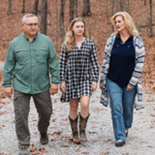 Adoptive parents and child walking in the woods in autumn.